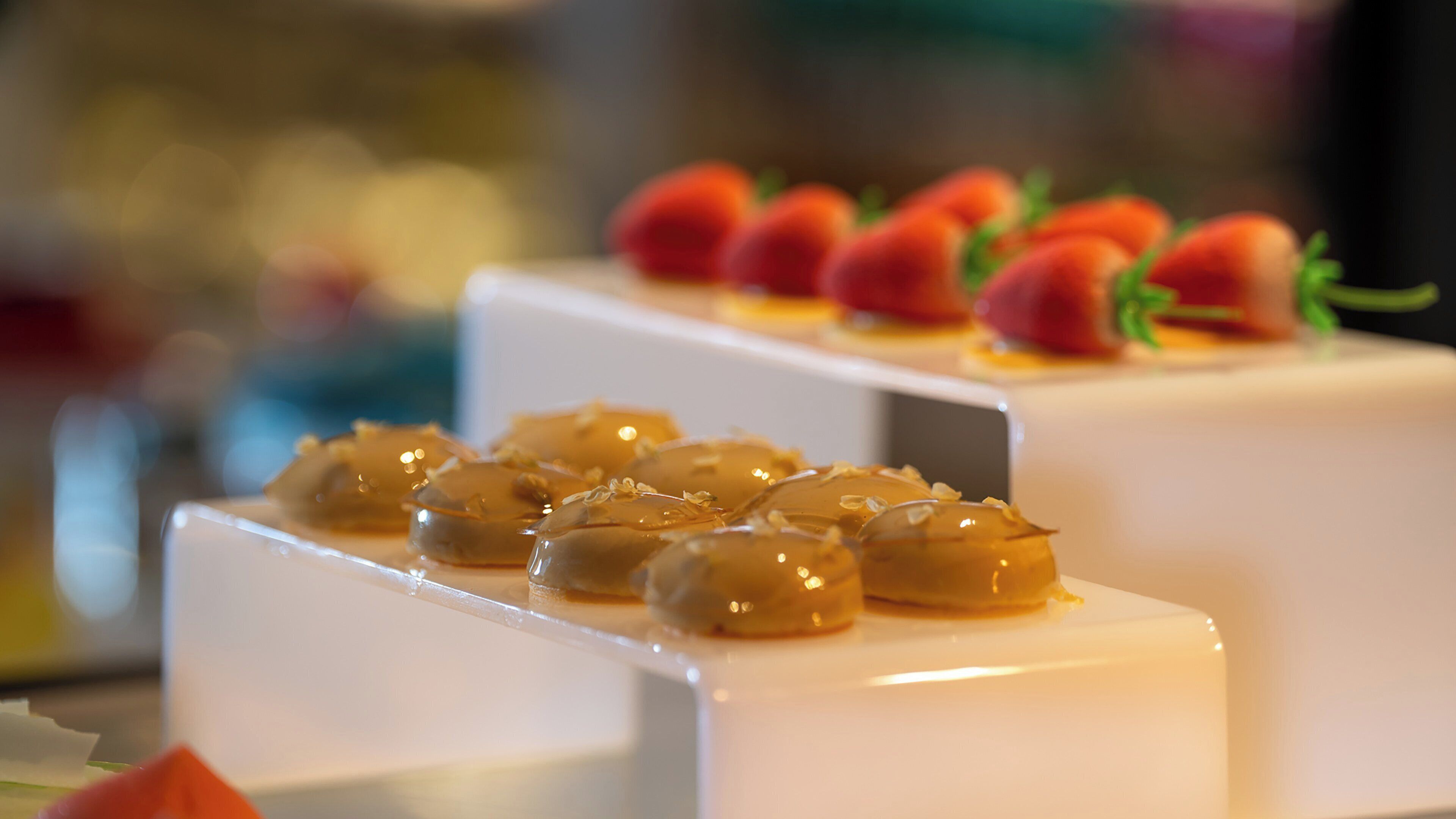 A dessert display with various sweets on white stands.