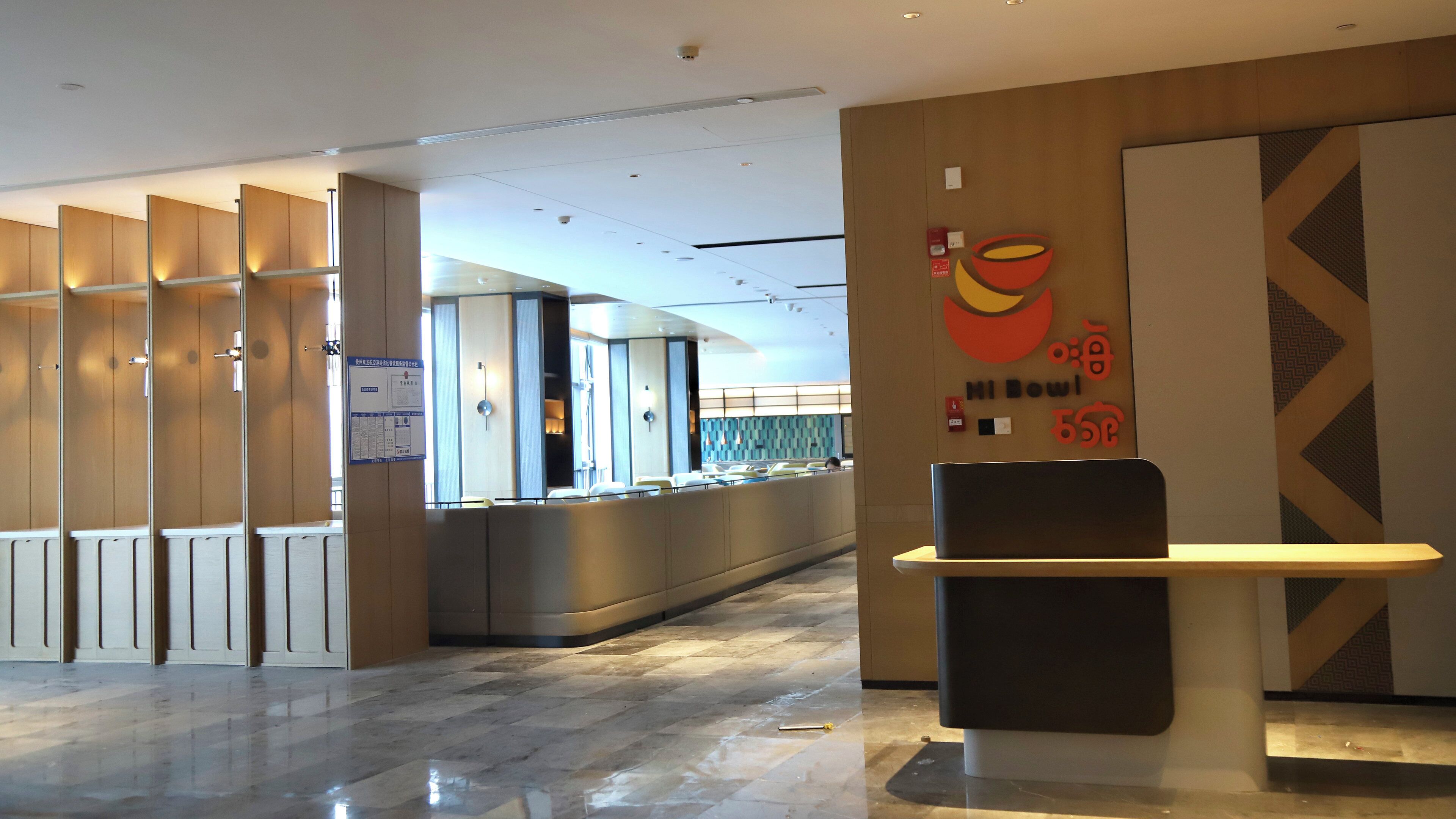 A hotel lobby with a reception desk, a seating area, and a wall with a sign.