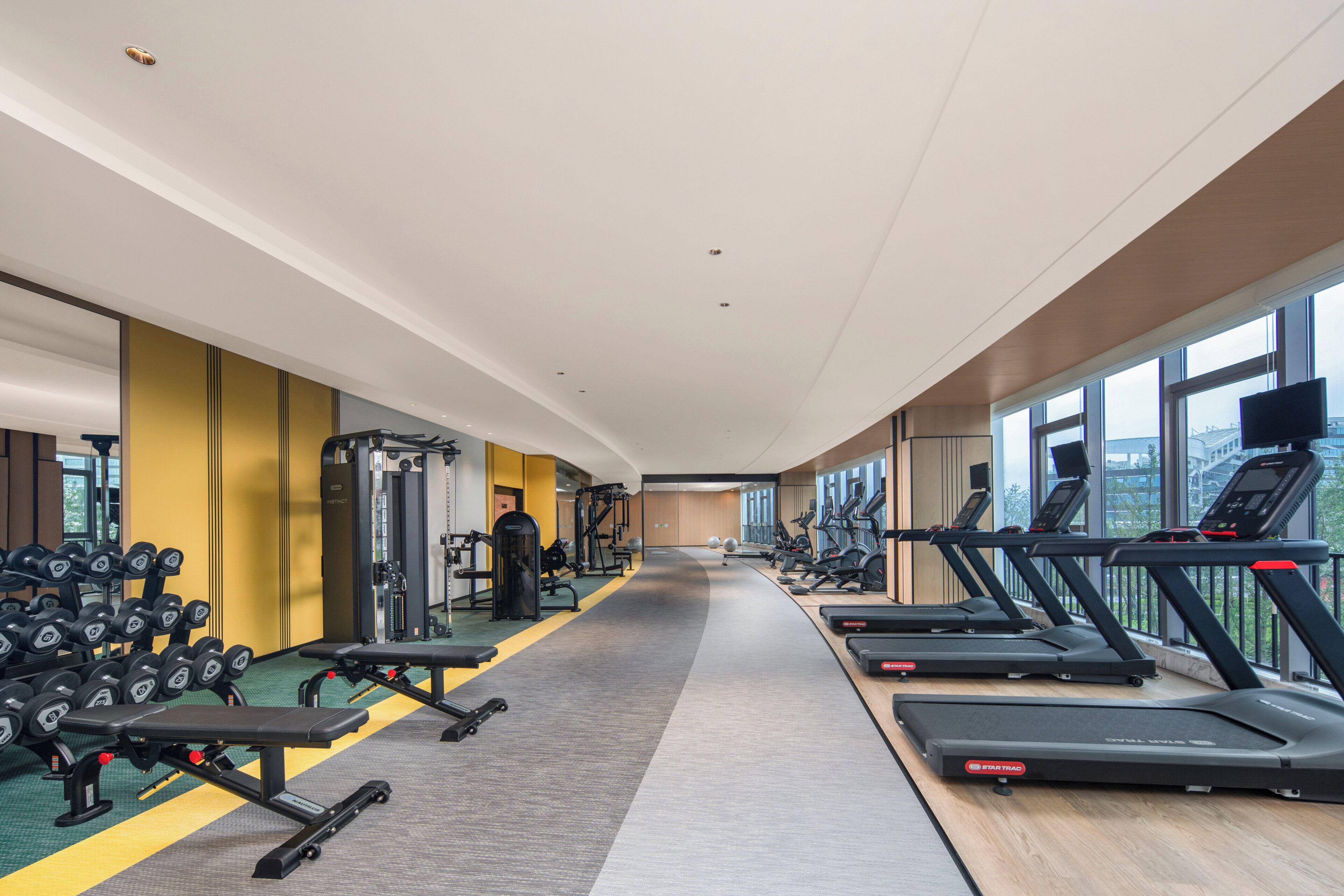 Une salle de sport équipée de tapis de course, d’haltères et d’appareils de musculation.