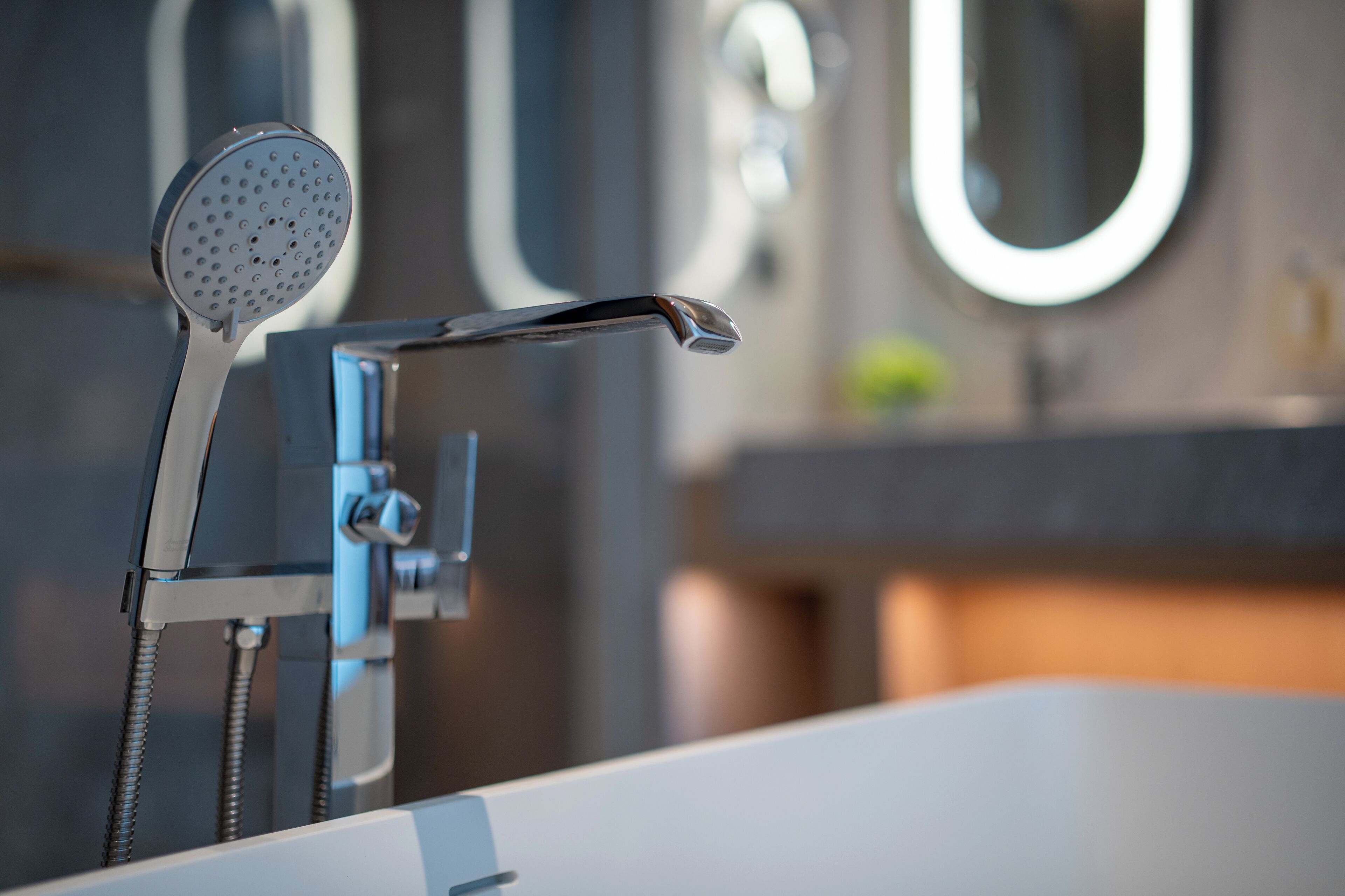 Une salle de bain moderne équipée d’une douche, d’un robinet et d’un miroir.