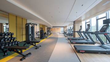A modern gym with treadmills, dumbbells, and weight machines.