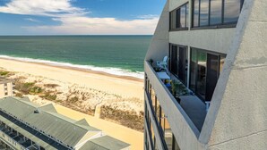 Un edificio moderno con un balcón que da a una playa y al océano.