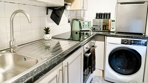 A modern kitchen with a stainless steel sink, a built-in washing machine, a coffee maker, and a toaster. - Cosy Hackney 1-bedroom Flat with Wi-fi, old street (London)