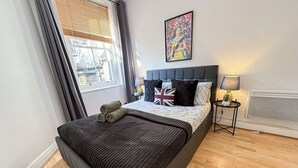 Una camera da letto con un letto, una finestra, un comodino con una lampada e un’opera d’arte a parete.