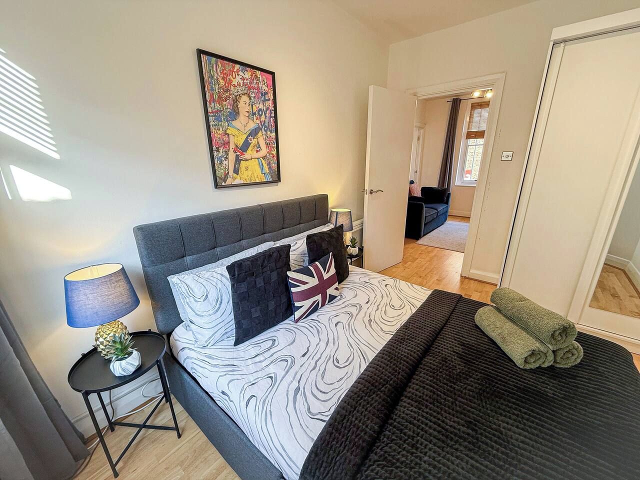 A bedroom with a bed, pillows, a lamp, and a painting on the wall.