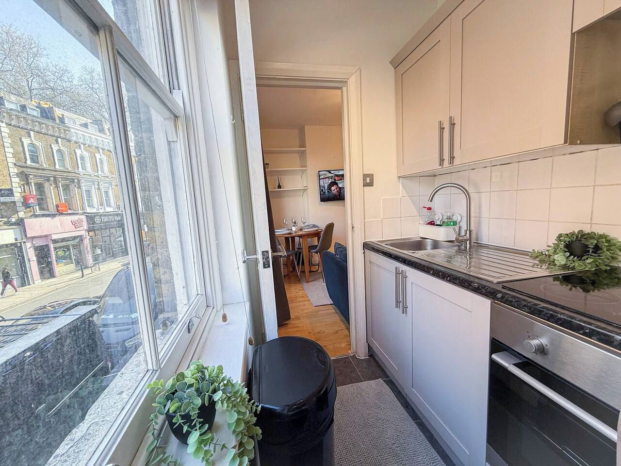 A compact kitchen with a window, a dining area, and a view of the street.