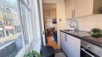 A compact kitchen with a window, a dining area, and a view of the street.