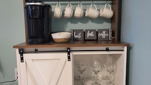 A kitchen counter with a coffee maker, mugs, and a sign that says "Coffee keeps me going until it's time for wine." - Beautiful Ocean Views! Amazing Amenities! King Size Bed!  (Myrtle Beach)