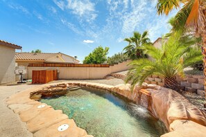 A swimming pool with clear water, surrounded by stone steps and palm trees.