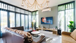 A modern living room with a sofa, a coffee table, and a TV mounted on the wall.