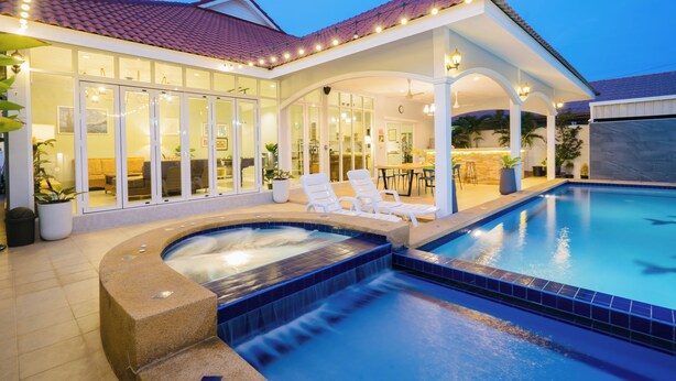 A poolside area with a hot tub, lounge chairs, and a covered patio.