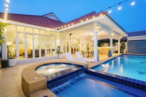 A poolside area with a hot tub, lounge chairs, and a covered patio.