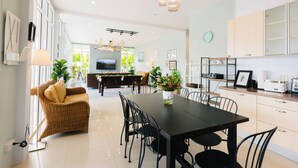 A modern kitchen with a dining area, featuring a pool table, potted plants, and a television in the background.