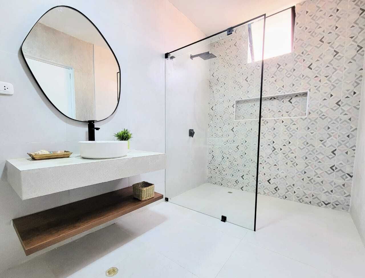 A modern bathroom with a glass-enclosed shower, a white sink with a mirror, and a patterned wall.