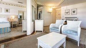 A hotel room with a bed, a small desk, two wicker chairs, a white table, and a mirror. - Studios frente ao mar no IL Campanario Resort ILCTOP (Florianópolis)