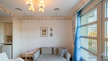 Un dormitorio con cama, escritorio, silla, teléfono y ventana con cortinas.