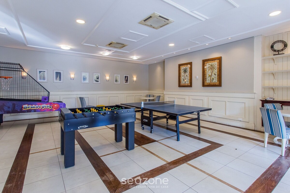 Una habitación con mesa de fútbol de mesa, mesa de ping pong y una mesa de fútbol de mesa con un diseño colorido.
