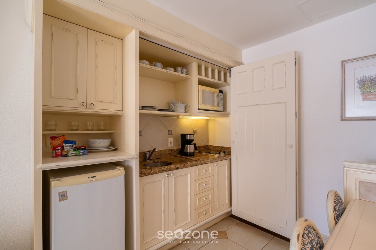 A compact kitchen with white cabinetry, a built-in microwave, and a coffee maker.