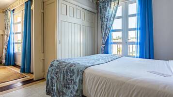 Un dormitorio con cama, armario y ventana con cortinas azules.