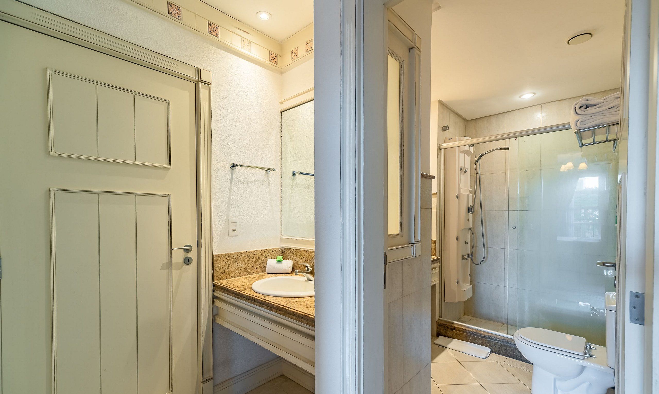 A bathroom with a toilet, sink, and shower area.