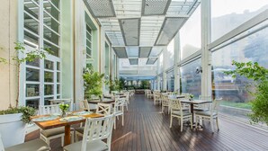 An indoor dining area with tables and chairs, large windows, and a wooden floor. - Studios frente ao mar no IL Campanario Resort ILCTOP (Florianópolis)