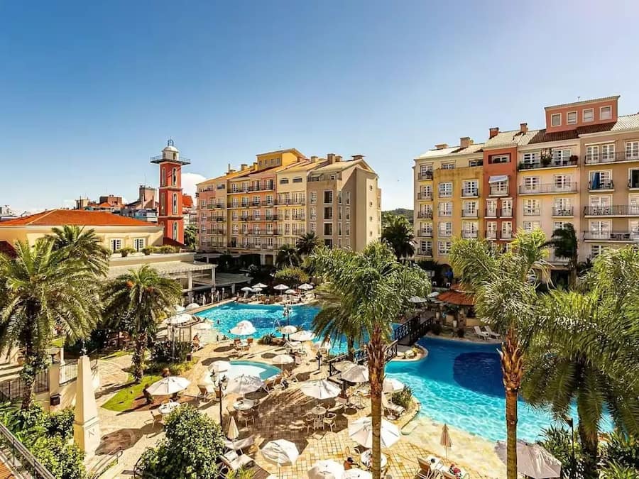 Un resort con piscina central, palmeras y edificios de varios pisos con balcones.