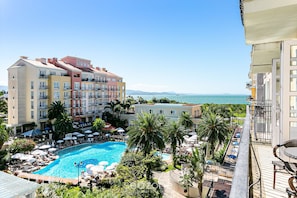 A hotel with a swimming pool surrounded by palm trees and lounge chairs. - Studios frente ao mar no IL Campanario Resort ILCTOP (Florianópolis)