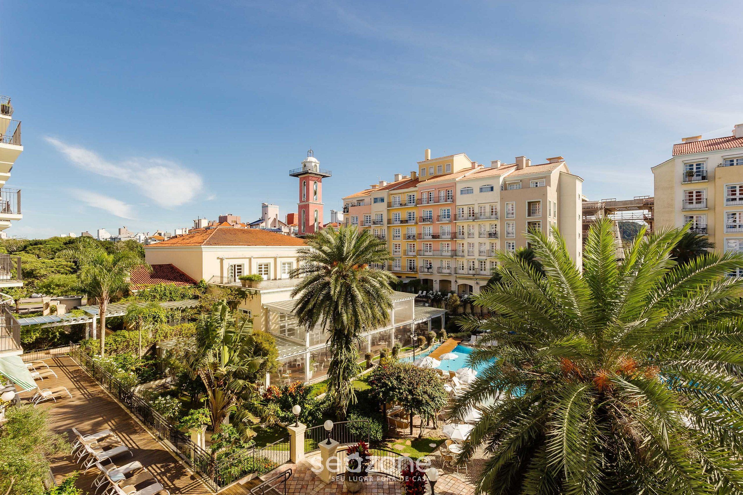 Un hotel con piscina, palmeras y una torre.
