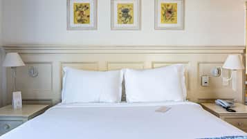 Habitación de hotel con una cama grande, dos mesitas de noche y tres cuadros enmarcados con motivos florales en la pared.