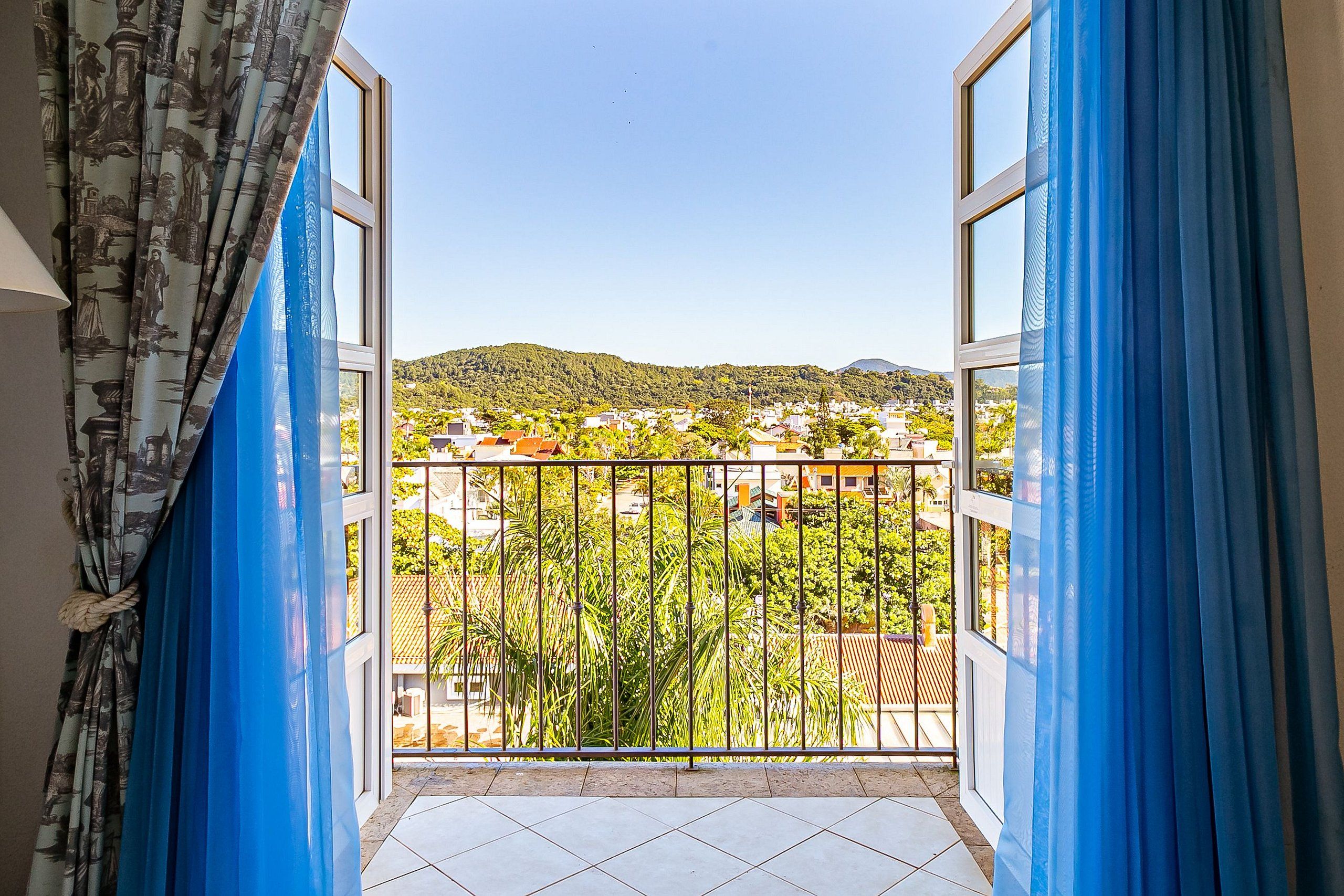 Ein Balkon mit Blick auf ein Wohngebiet, einem Metallgeländer und blauen Vorhängen.