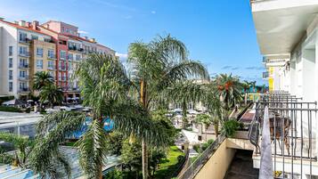 A multi-story hotel with balconies, palm trees, and a clear blue sky.