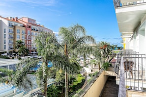 Un hotel de varios pisos con balcones, palmeras y un cielo azul despejado.