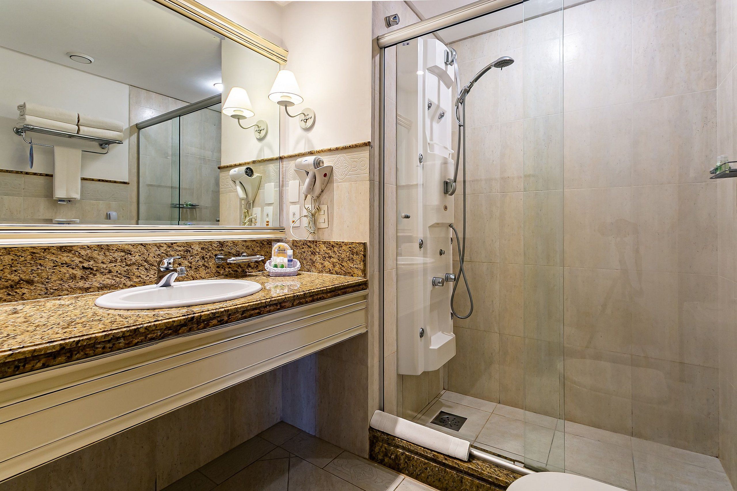 A modern bathroom with a sink, mirror, and glass-enclosed shower.