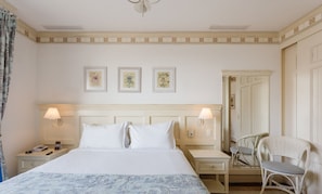 Una habitación de hotel con una cama, dos lámparas de noche, una mesita de noche, una silla y una puerta.