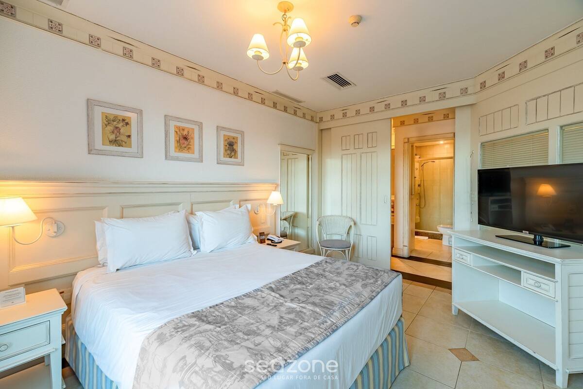 Una habitación de hotel con una cama grande, televisión, escritorio y una silla.