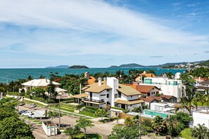 Zona residencial costera con casas modernas, un estacionamiento y vistas al mar y a islas distantes.