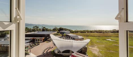 A modern building with a unique architectural design, a spacious outdoor area, and a view of the sea.