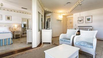 Habitación de hotel con cama, un pequeño escritorio, dos sillas de mimbre, una mesa blanca y un espejo.