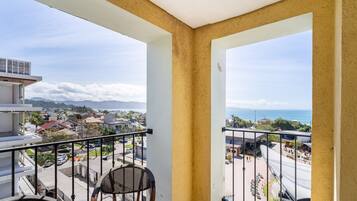 A balcony with a view of a coastal town, a chair, and a building with a sign that reads "DURAN".