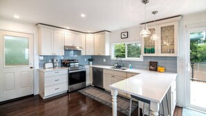 A modern kitchen with white cabinets, stainless steel appliances, and a large island. - Beachfront | Sandy Shore, Near Mt. Washington (Campbell River)