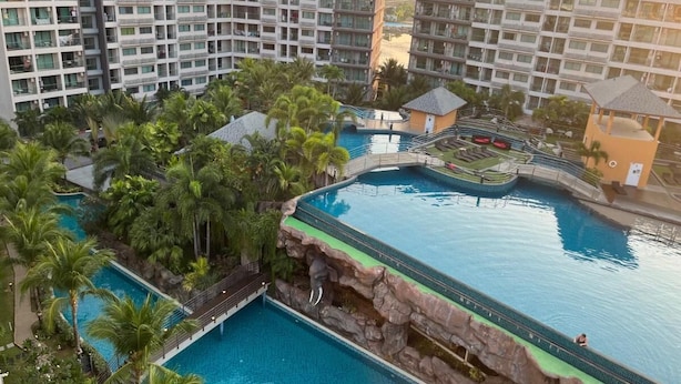 Ett semesterparadis med flera pooler, palmer och moderna byggnader.