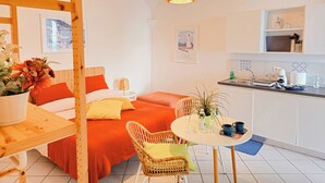 A modern hotel room with a bed, a dining table, a kitchen area, and a hanging light fixture. - Raito Guest House - Amalfi Coast (Vietri sul Mare)