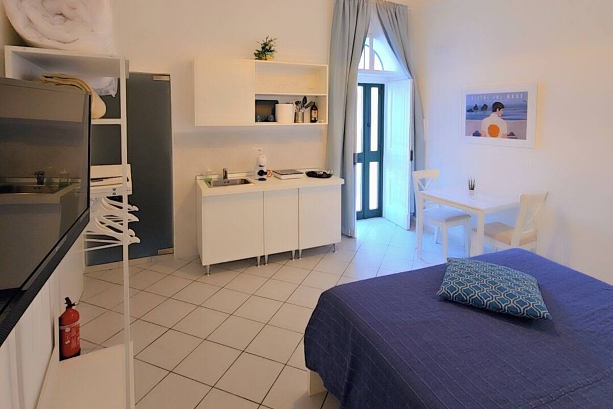 Ein kompaktes Hotelzimmer mit Bett, Küchenzeile, Essecke und Bad.