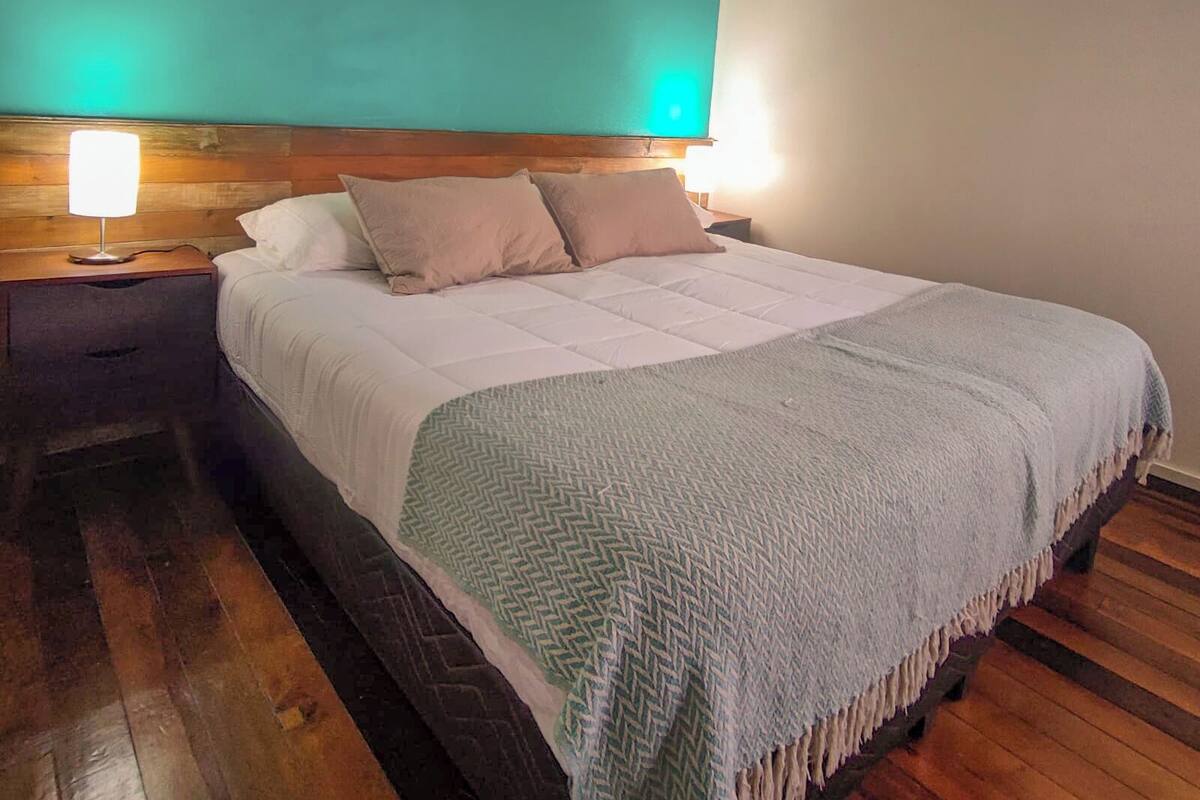 Un dormitorio con cama, mesita de noche y lámpara.