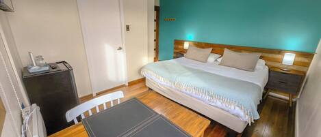 Un dormitorio con cama, mesitas de noche, escritorio y silla.