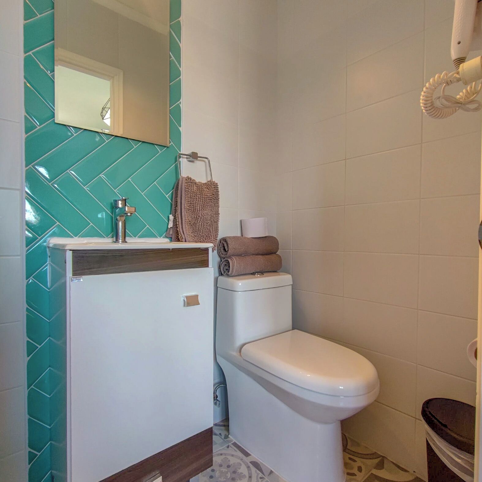 A bathroom with a white toilet, a sink with a mirror above it, and a towel rack with towels.