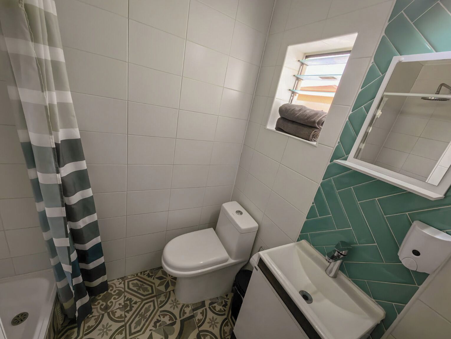 Een badkamer met toilet, wastafel en raam met handdoekhouder.