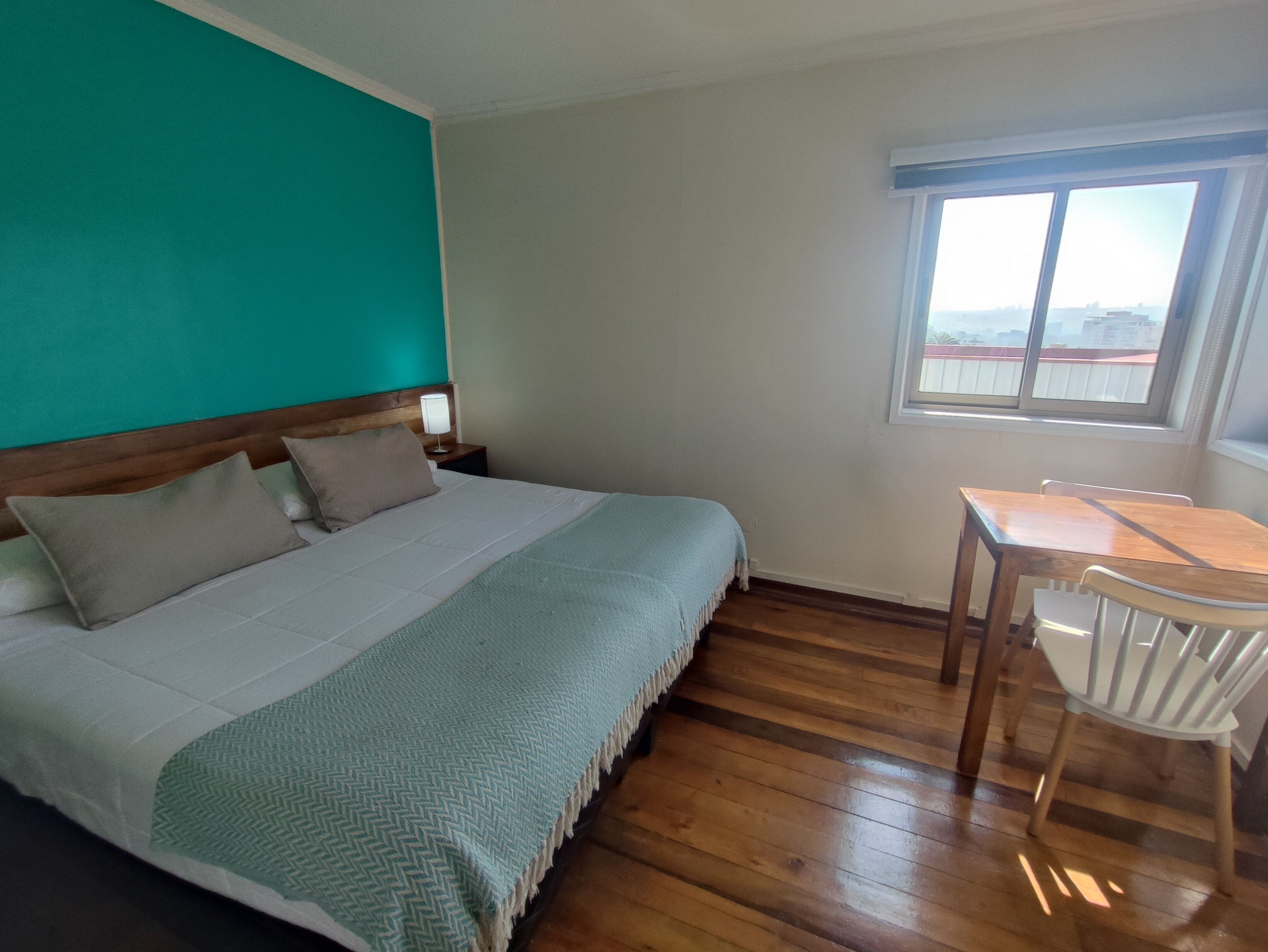 A bedroom with a bed, a nightstand, a table, and a chair.