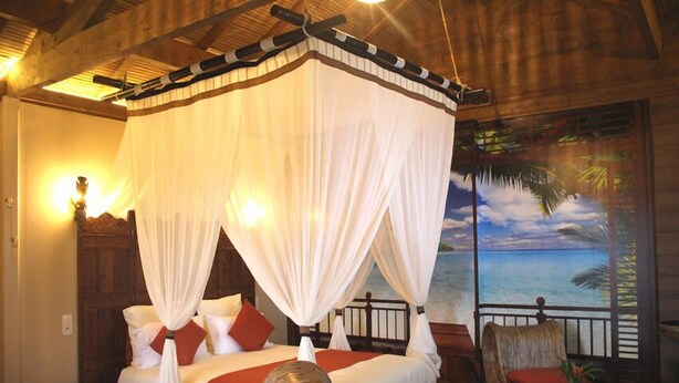 A room with a four-poster bed, a balcony with a view of the sea, and a tropical-themed mural. - Sweet-Dreams (Trois-Rivières)