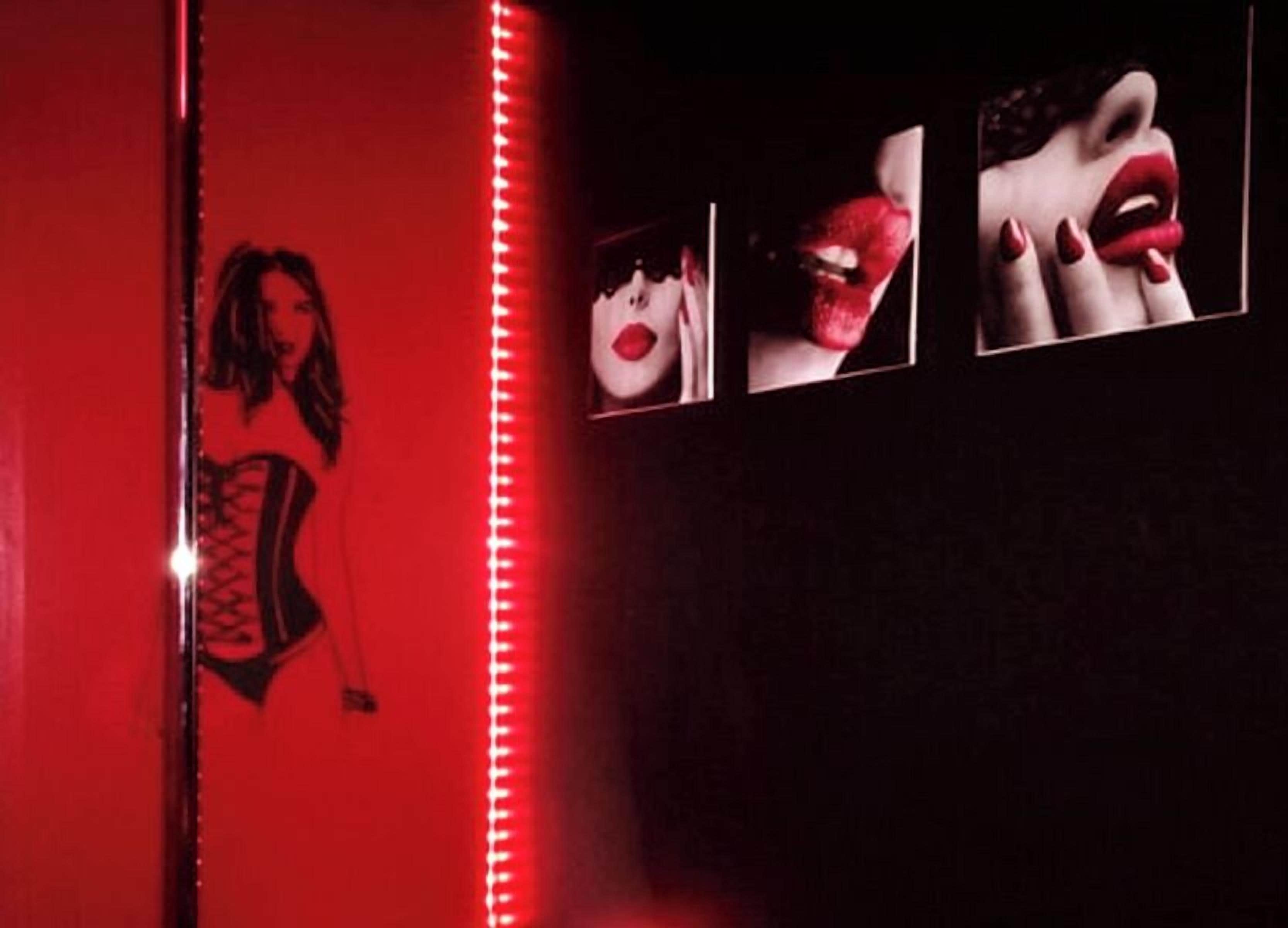 A red-lit room with a mirror reflecting a person in a corset.